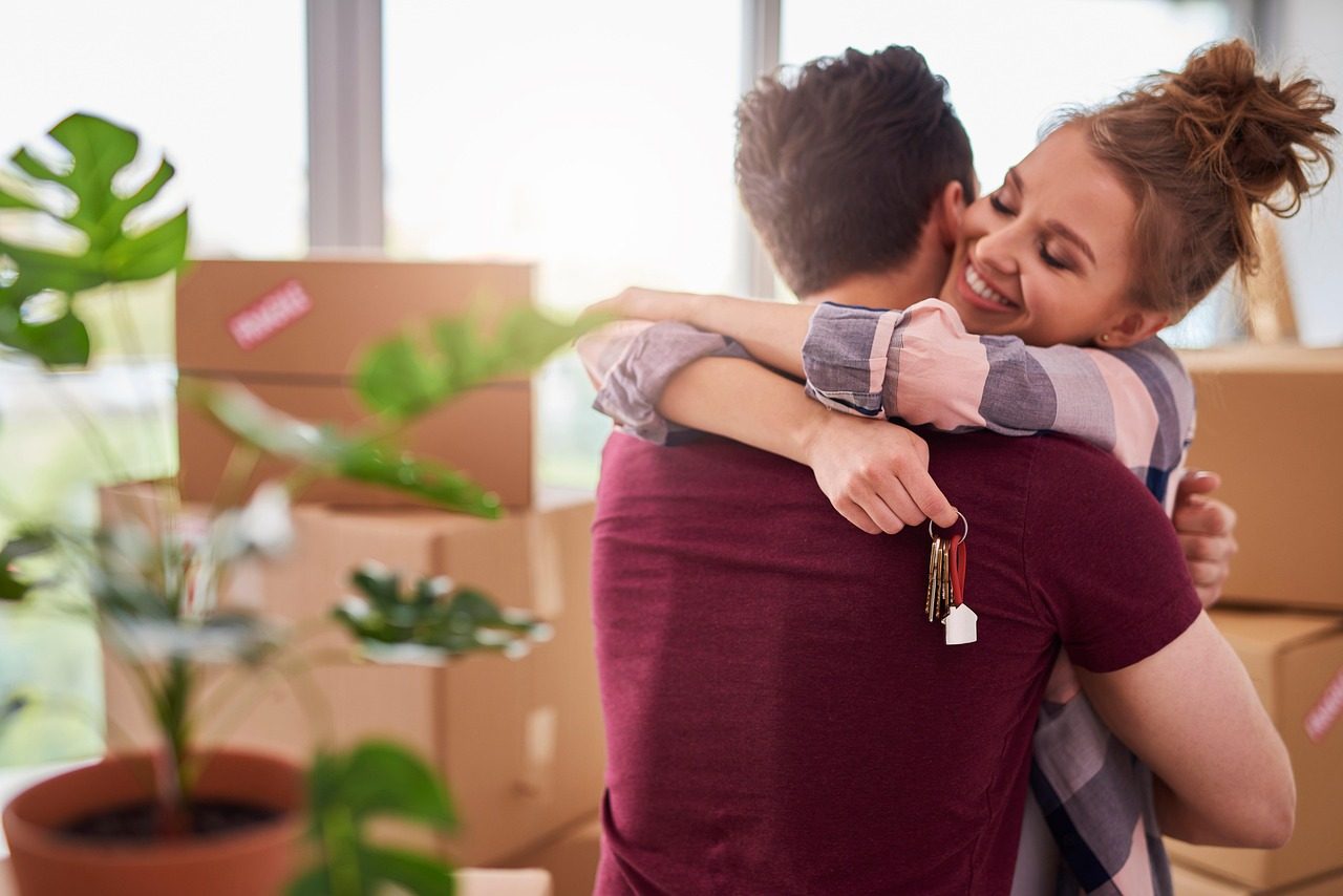 A couple holding keys to their new Phoenix home amid moving boxes